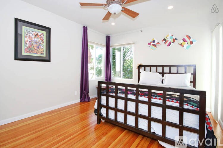 A bedroom with a bed, a ceiling fan, and a picture on the wall.