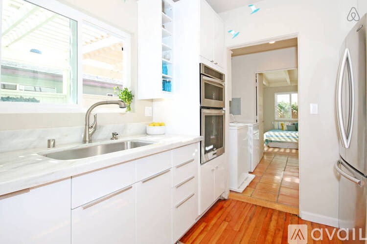A kitchen with white cabinets and a wooden floor.