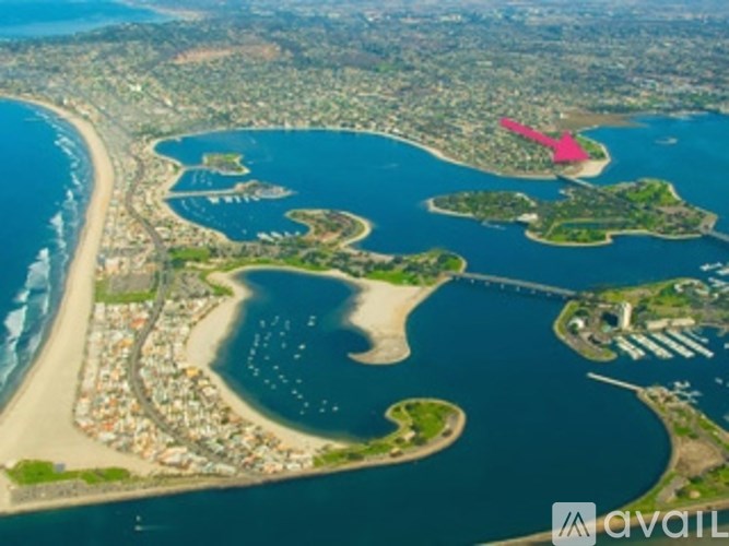 A bird's eye view of a coastal area with a large body of water and a small island with a pink area on it.