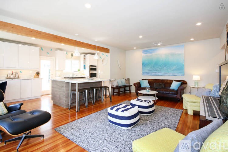 A living room with a blue and white striped ottoman in the center.
