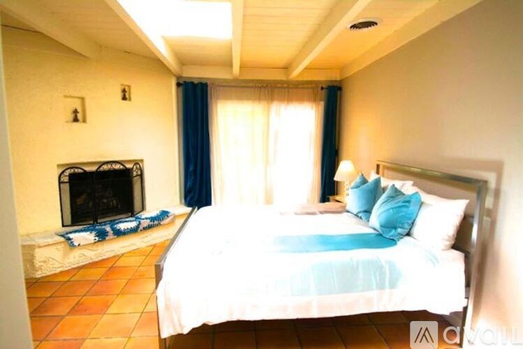 A bedroom with a bed, a fireplace, and a window with curtains.