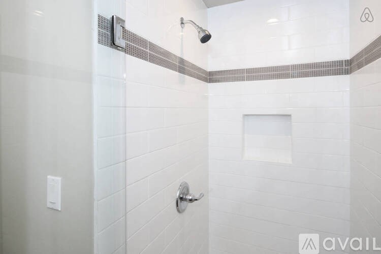 A modern bathroom with a glass shower enclosure and a white tiled wall.