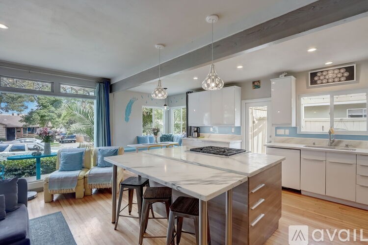 A modern kitchen with a large island and a view of the street outside.