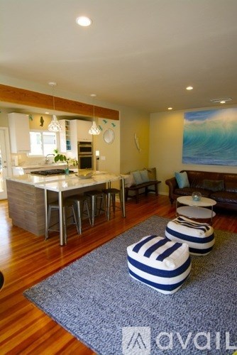A modern kitchen with a dining area and a painting of a wave on the wall.