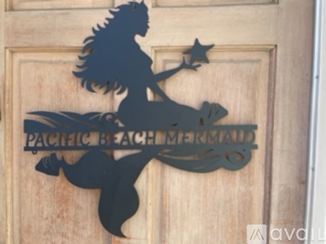 A wooden door with a silhouette of a mermaid and the words "Pacific Beach Mermaid" engraved on it.