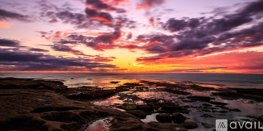 A beautiful sunset over the ocean with rocks in the foreground.