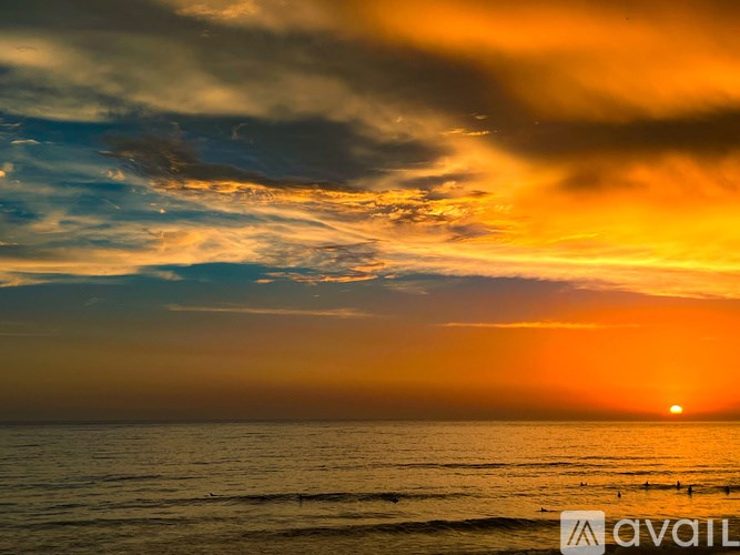 A beautiful sunset over the ocean with a few birds flying.