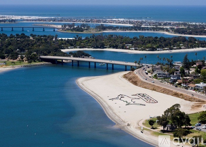 A bridge spans a body of water with a sandy beach in front.