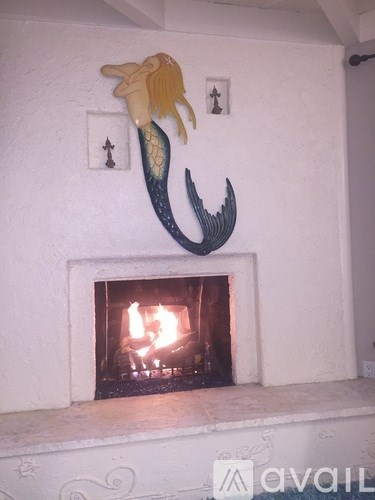 A mermaid decoration is above a fireplace.
