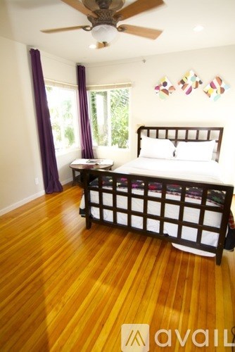 A bedroom with a bed, a table, and a ceiling fan.