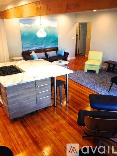 A living room with a couch, chair, and a painting of a light bulb hanging from the ceiling.