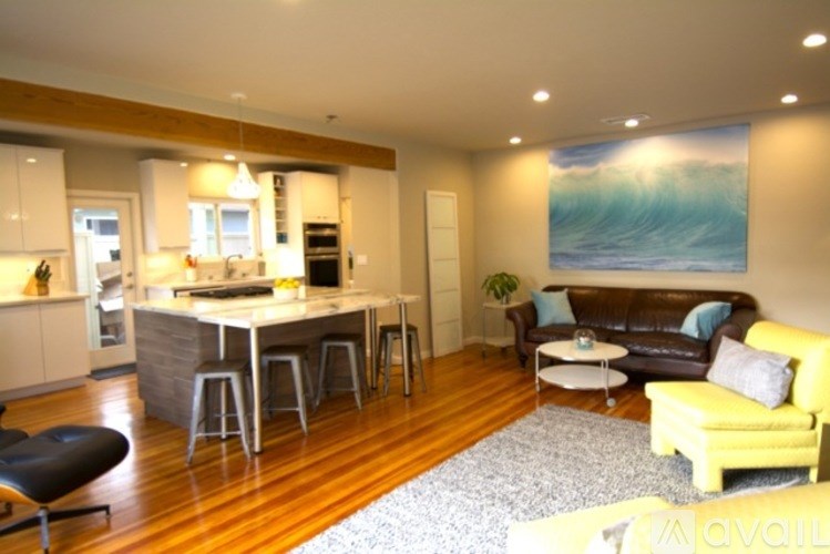 A living room with a couch, a chair, and a painting of a wave on the wall.