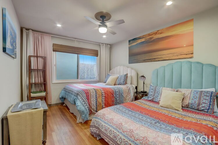 A bedroom with two beds and a ceiling fan.