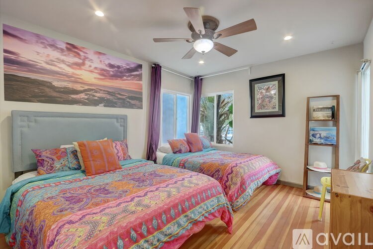 A bedroom with two beds and a ceiling fan.