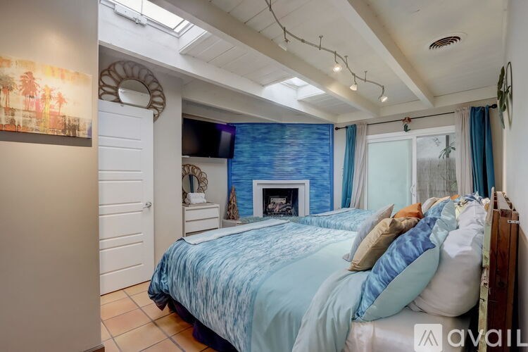 A bedroom with a blue bedspread and a fireplace.