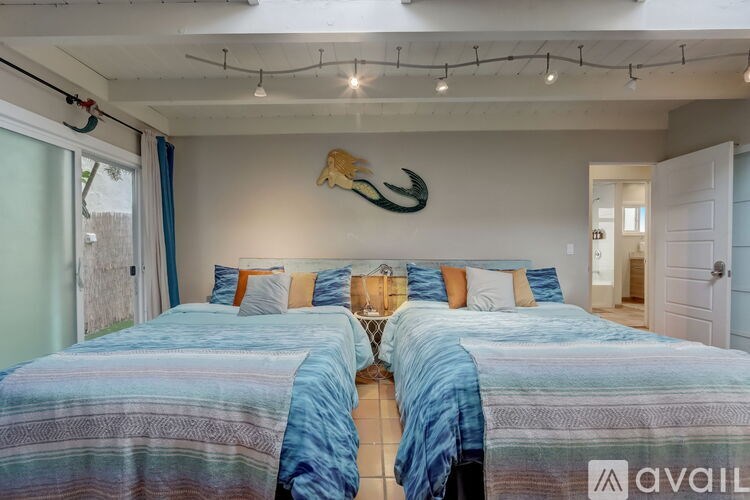 A bedroom with two beds and a wall hanging of a fish.