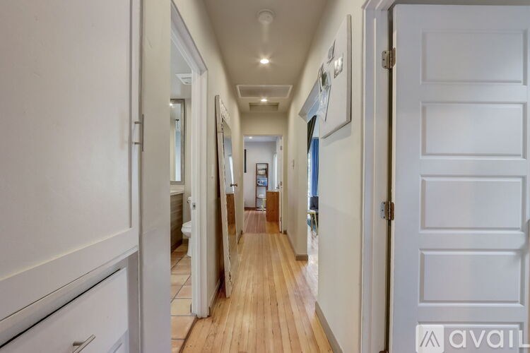 A long hallway with white doors and a wooden floor.