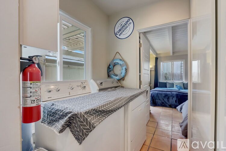A white washing machine is in a room with a blue bed in the background.