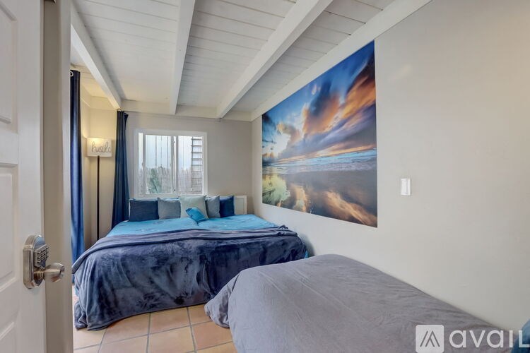 A bedroom with a large bed and a painting on the wall.