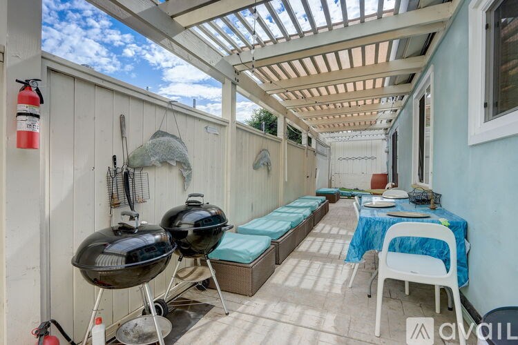 A patio with a grill and a table set up for an outdoor meal.