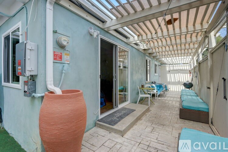 A large orange vase is sitting on a patio with a blue wall and a white ceiling.