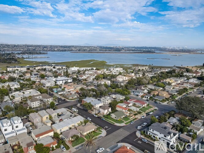 A residential area with houses and a body of water in the distance.
