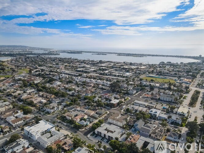 A bird's eye view of a residential area with a body of water in the distance.