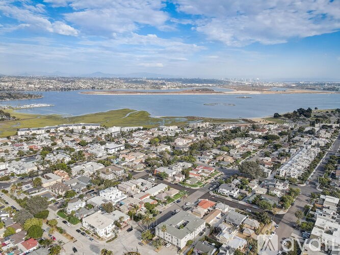 A bird's eye view of a residential area with a large body of water in the background.