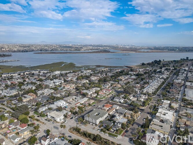 A bird's eye view of a residential area with a body of water in the distance.