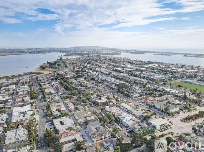 A bird's eye view of a residential area with a body of water in the background.