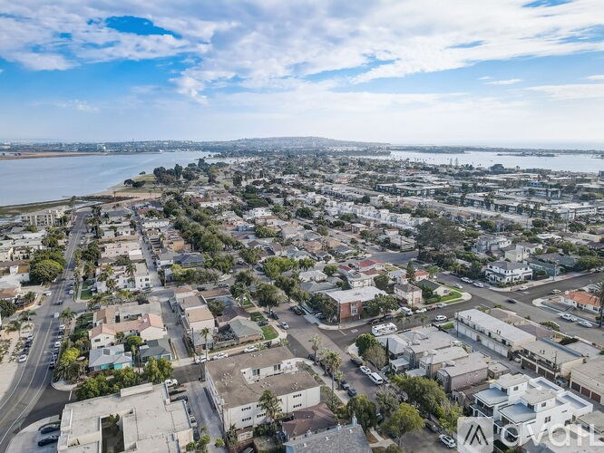 A bird's eye view of a residential area with a body of water in the distance.