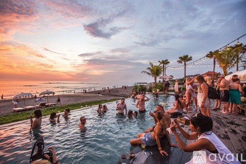 A group of people are enjoying a sunset by the pool.