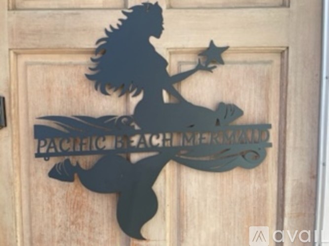 A silhouette of a mermaid is on a wooden door with the words "Pacific Beach Mermaid" written underneath.