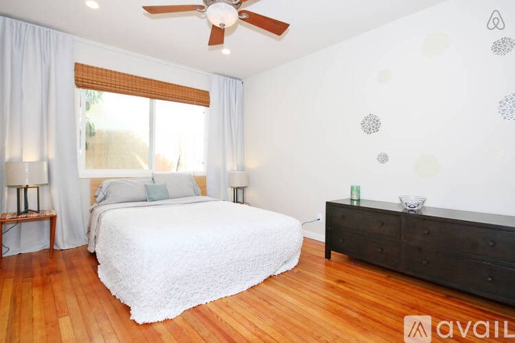 A bedroom with a bed, dresser, and ceiling fan.