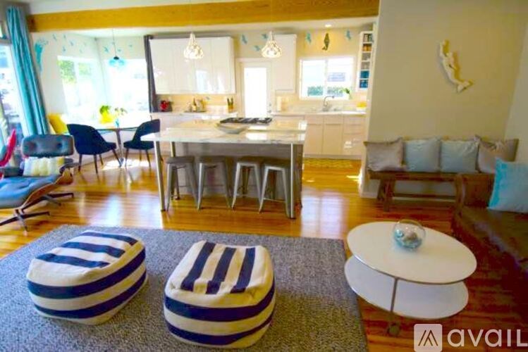 A living room with a white sofa and a dining table with chairs.