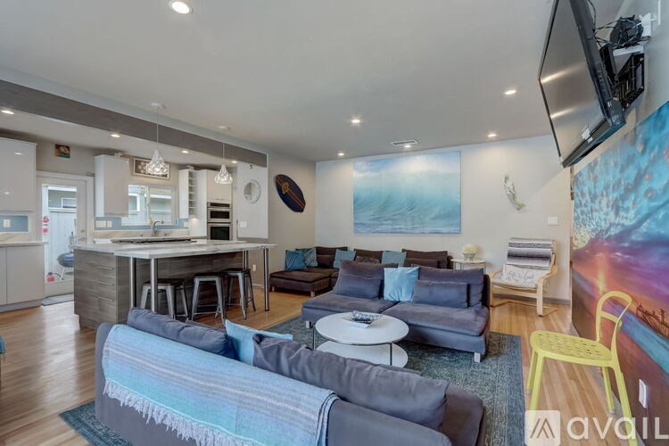 A living room with a grey couch and a television mounted on the wall.