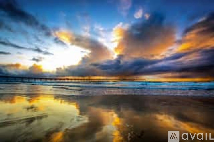 A beautiful beach scene with the sun setting over the horizon.