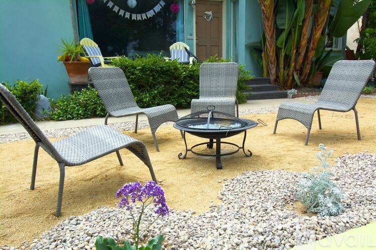 A patio with a fire pit and chairs.