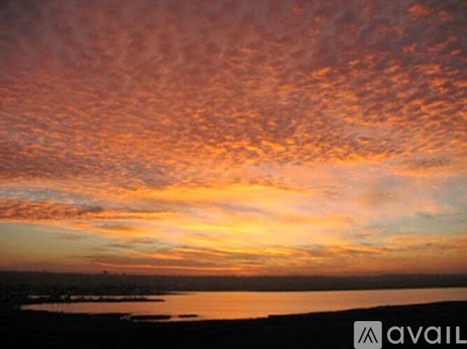 A beautiful sunset over a body of water with a cloudy sky.