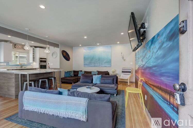 A living room with a grey couch and a large painting on the wall.