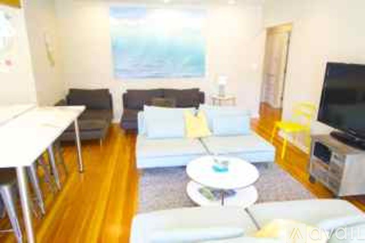 A living room with a white couch, a white coffee table, and a television.