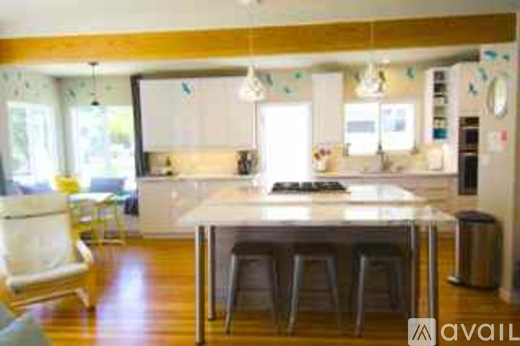 A kitchen with a white island and bar stools.
