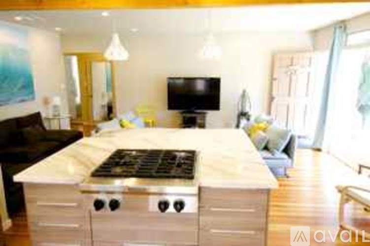 A modern kitchen with a large island and a TV mounted on the wall.