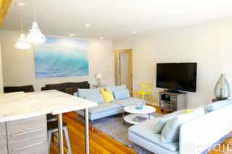 A living room with a white couch and a painting on the wall.