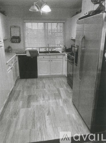 A kitchen with a refrigerator, sink, and cabinets.