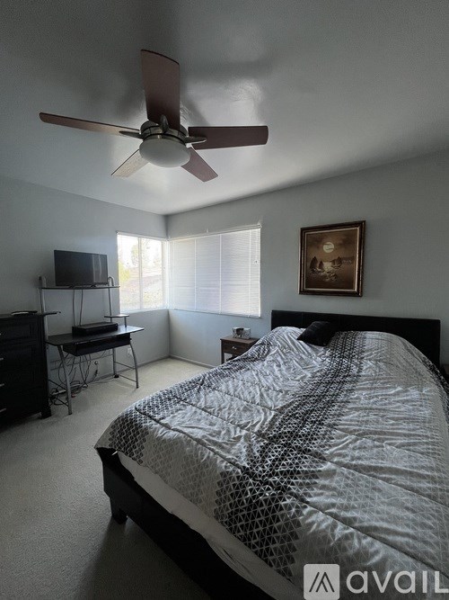 A bedroom with a bed, a fan, and a television.