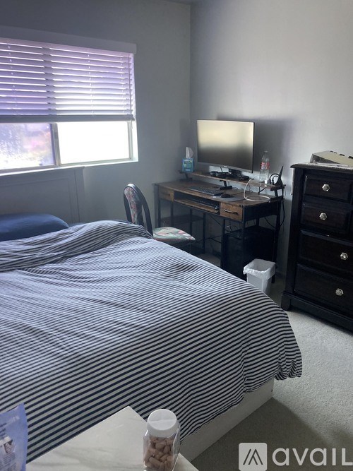A bedroom with a bed, desk, and window.