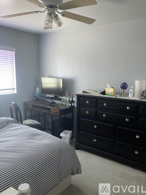 A room with a bed, a desk with a television, and a dresser.