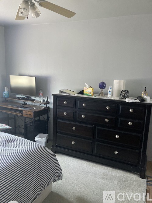 A black dresser with a mirror and a television on a desk in a room.