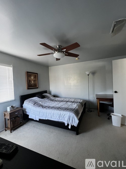 A bedroom with a bed, nightstand, and a ceiling fan.